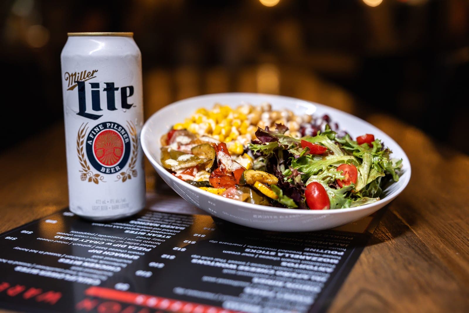 Grilled veggie power bowl with a cold beer on a warehouse table