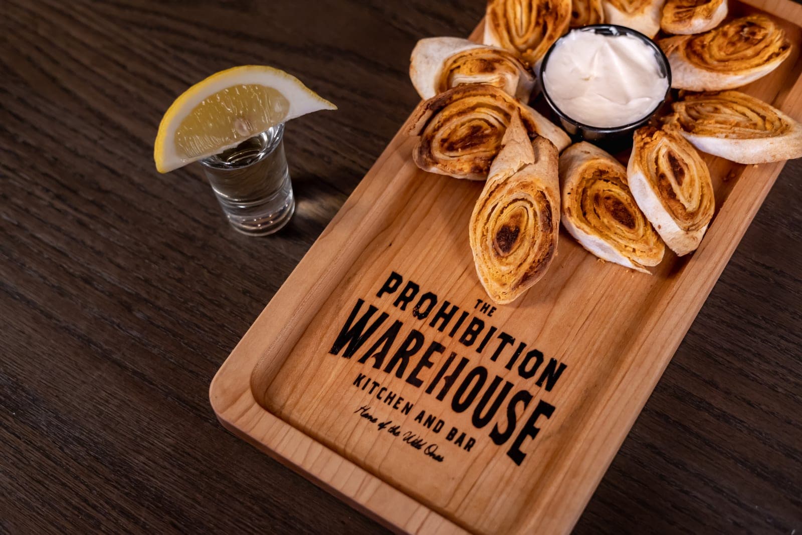 A branded Prohibition Warehouse serving board with pinwheels and a shot